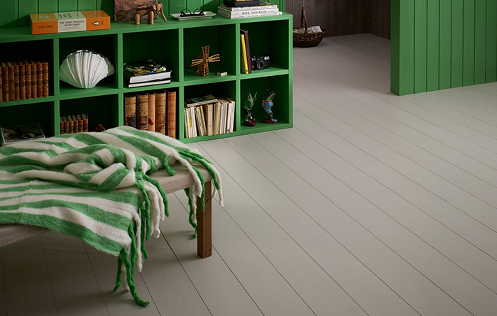 Gråmålat trägolv med gröna möbler