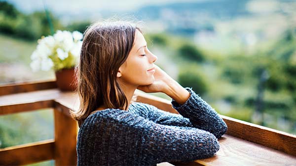 Kvinna utomhus som lutar sig mot ett träräcke