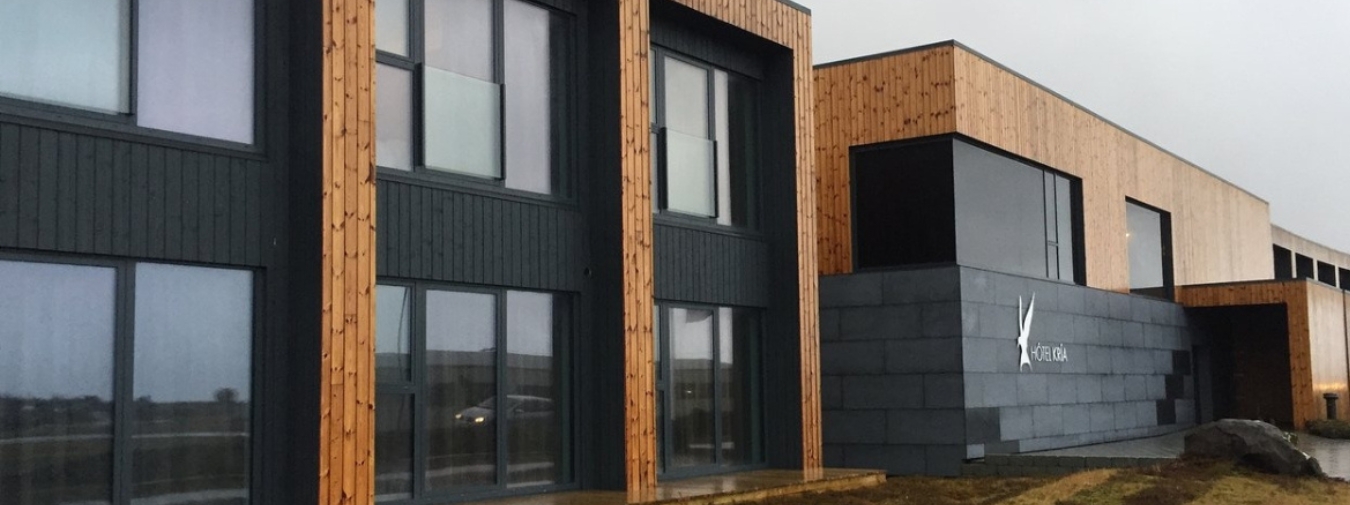 Zweistöckiges Modulgebäude mit großen Fenstern, hellbrauner und schwarzer Holzverkleidung.