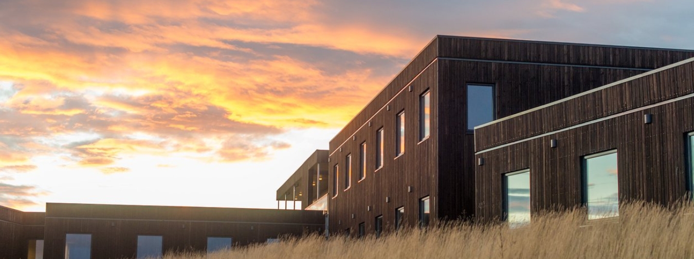 Brown modular building with a colorful sky in the background.