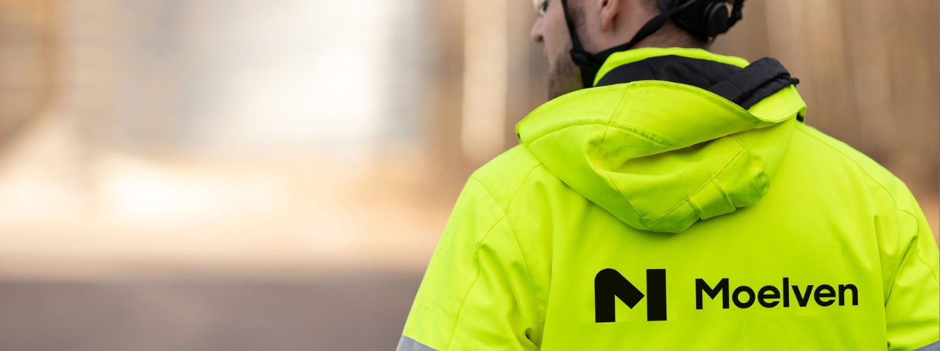 Person wearing a high-visibility vest with the Moelven logo on the back.