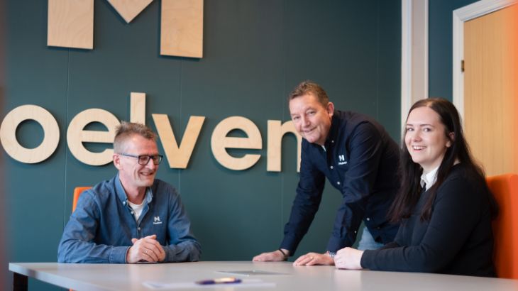 Tre smilende Moelven-kolleger rundt et bord.