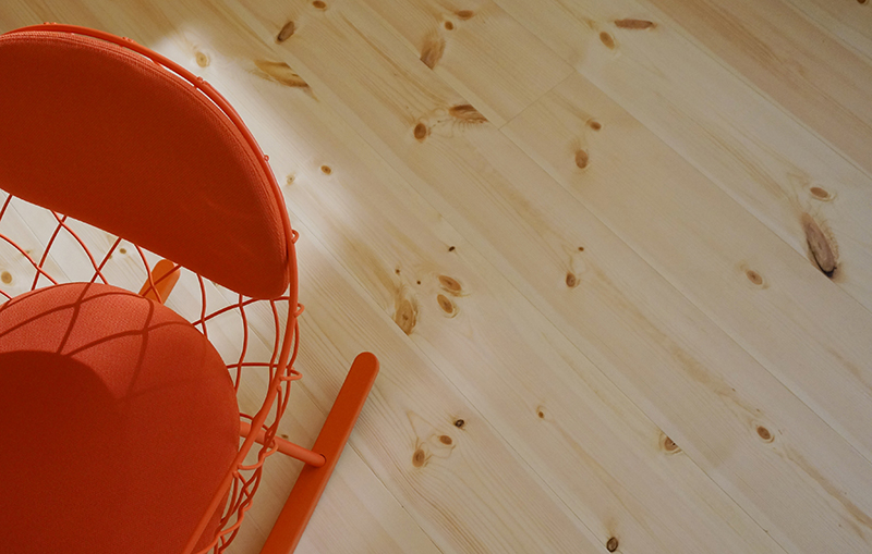 Ljust trägolv och en orange stol